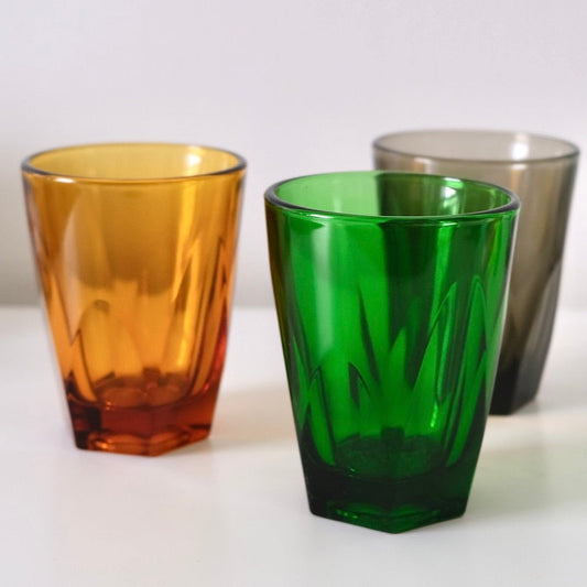 Three colored glass tumblers (orange, green, gray) on a white background

